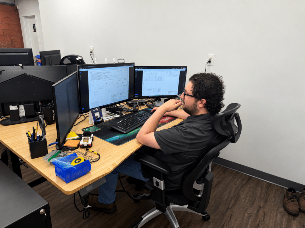 Lite Coms electrical engineer Kyle reviewing technical drawings and engineering documentation at his workstation.