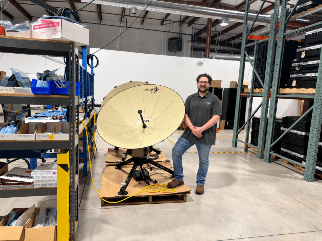 Lite Coms electrical engineer Kyle standing beside a deployable satellite communications terminal.
